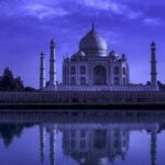 Taj Mahal Night Tour – Full Moon View at Night A full moon night view of the Taj Mahal reflected in water, captured during the Taj Mahal Night Tour with glowing marble and a peaceful blue sky.