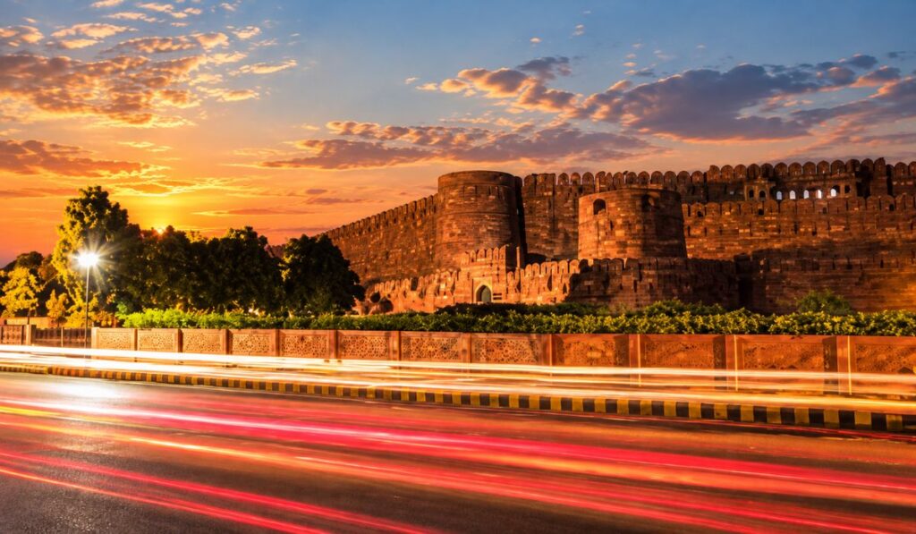 Illuminated red sandstone walls and bastions of Agra Fort at dusk
